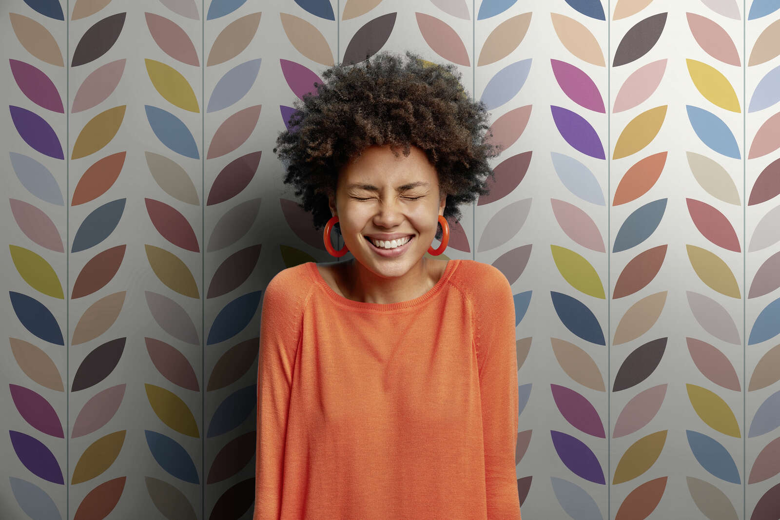 orange top, langarmshirt, große rote ohrringe, mode-accessoire, gemusteter hintergrund