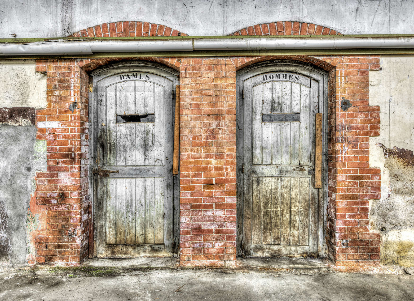             Fototapete Steinwand mit Vintage Toilettentüren – Grau, Orange, Beige
        