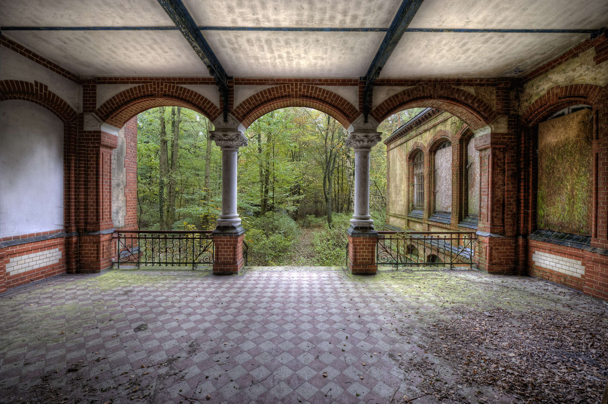 verlassene veranda, breite balken, steinpfeiler, roter ziegel, durchblick ins grün