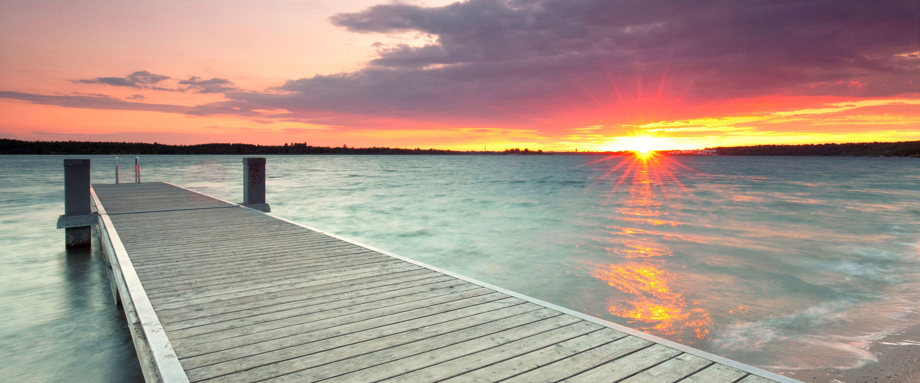             Fototapete Holzsteg im Wasser bei Sonnenuntergang
        