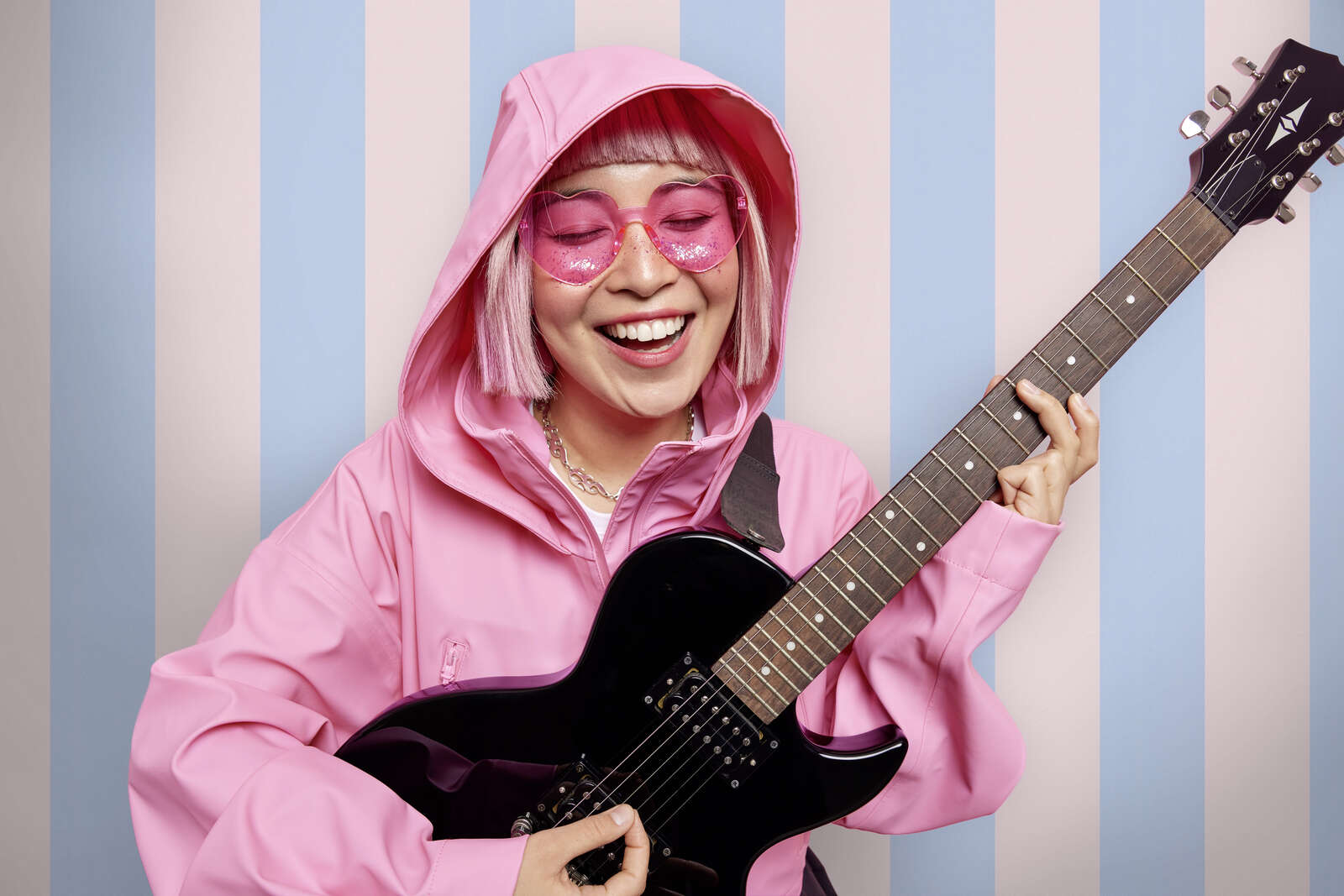 pink outfit, hooded jacket, guitar, pink sunglasses, striped background