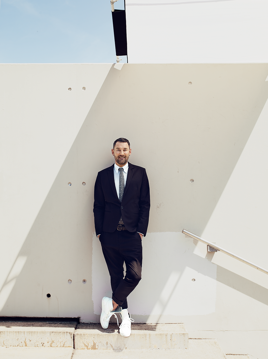 Photo Michael Michalsky in suit, full body shot in front of bright concrete wall