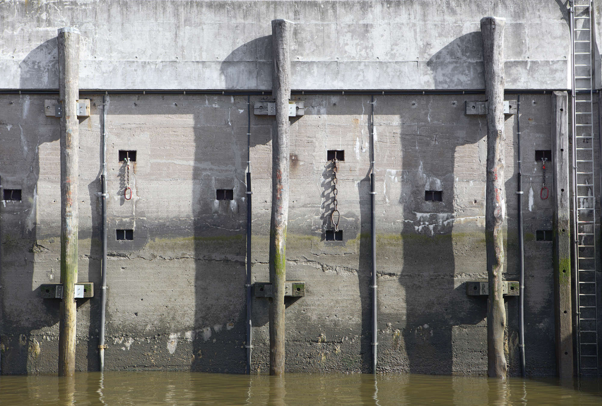             Urban Style Fototapete – Vliestapete mit massiver Betonstruktur am Hafen – Grau, Grün
        